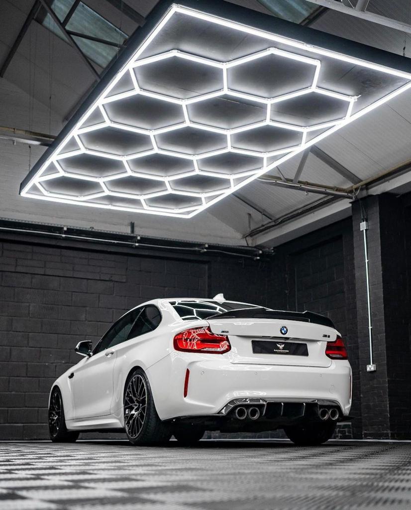 Valge auto valgustatud tuff-lite kuusnurksete LED valgustitega, seismas tuff-tile põrandaplaatide peal