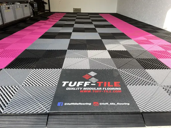 Roosa Tuff-tile põrandaplaat koos logoplaadiga, millel tootja Tuff-Tile logo. 