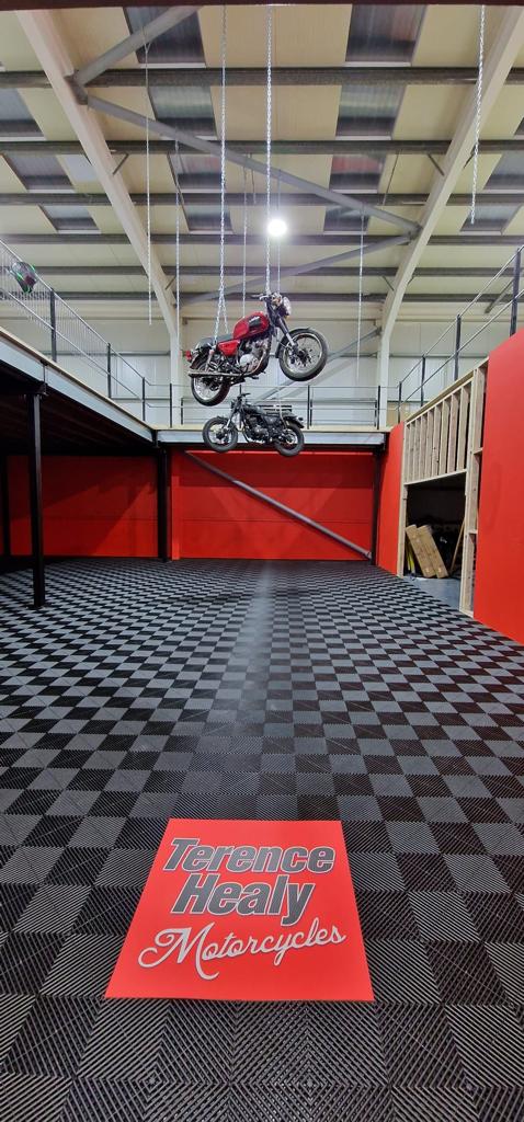 Motorcycles hanging from the sealing above the floor coverd in tuff-tile flooring